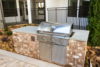 A stainless steel outdoor grill is built into a brick wall.